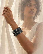 Dark green printed fabric bangles worn beside a sheer curtain