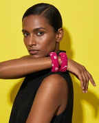 Magenta floral fabric bangles worn with a black top against a yellow backdrop
