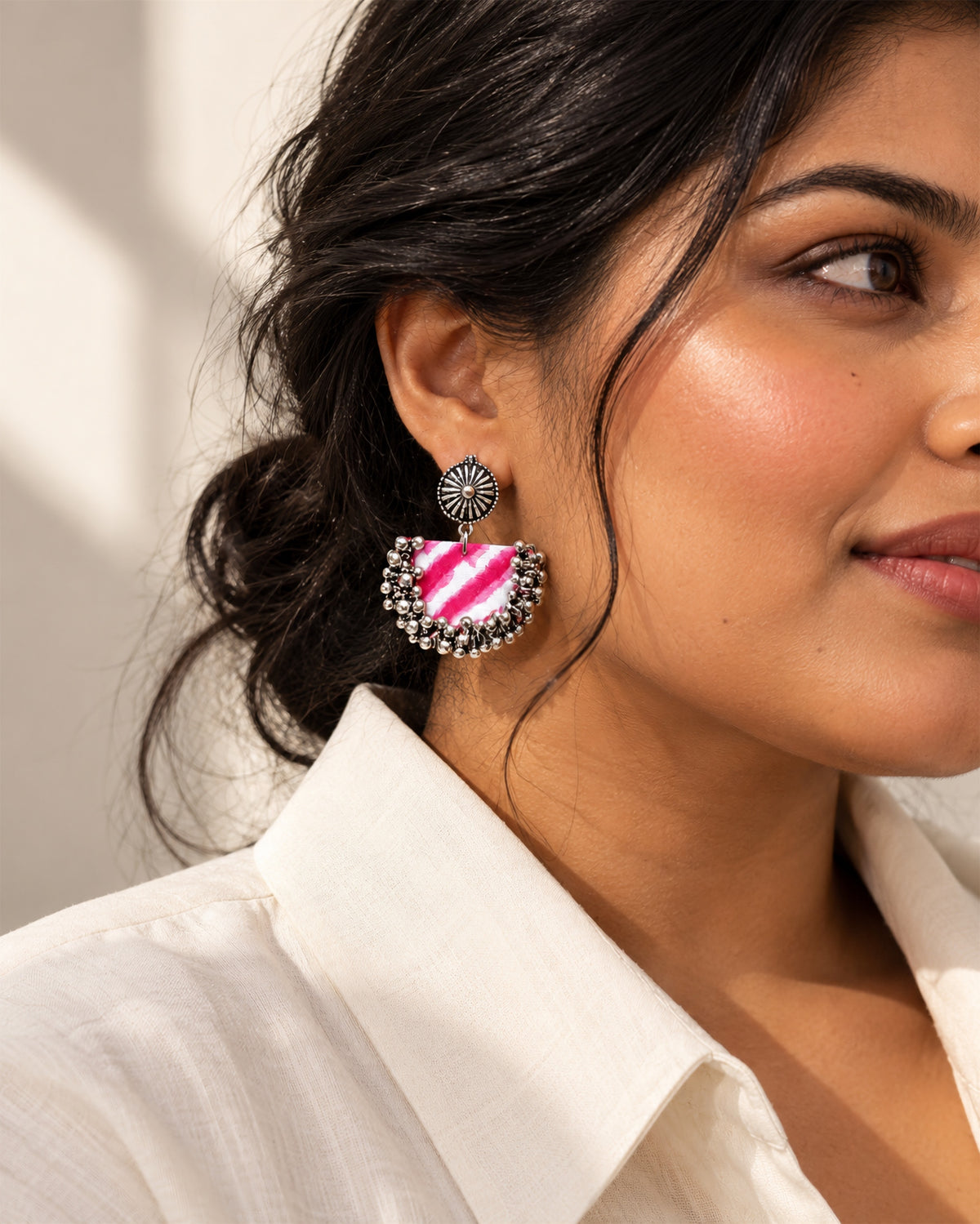 Rani Pink Chandbali Earrings with Ghungroo worn with a white cotton shirt and a low bun in morning light: tie-dyed pink and white crescent edged with silver ghungroo bells