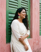 Fuchsia Pink Geometric Ghungroo Earrings worn with an ivory cotton kurta beside green wooden shutters (AI-generated styling image)
