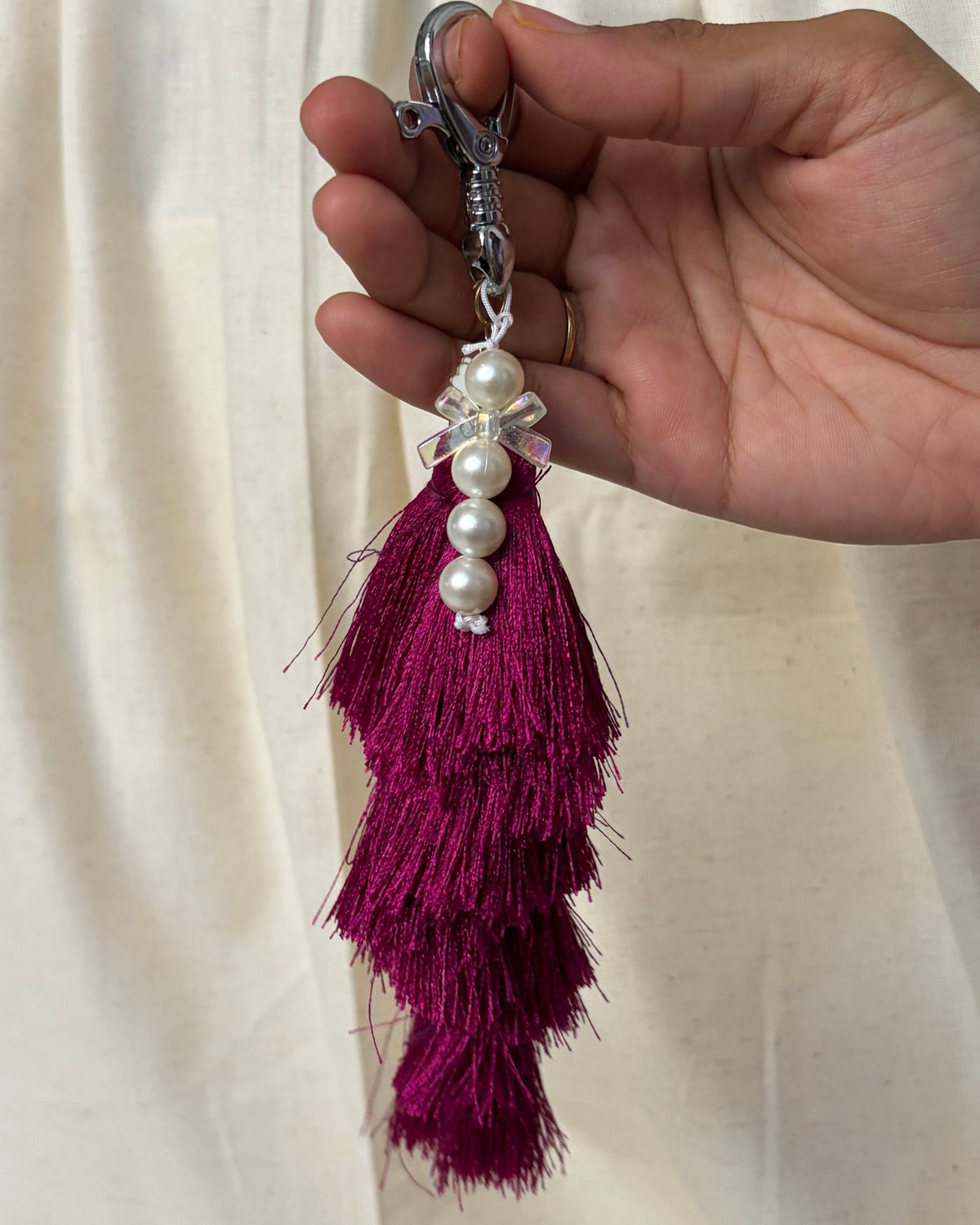 Gulabi silk tassel bag charm held in the hand to show its size, about 9 inches from clasp to fringe