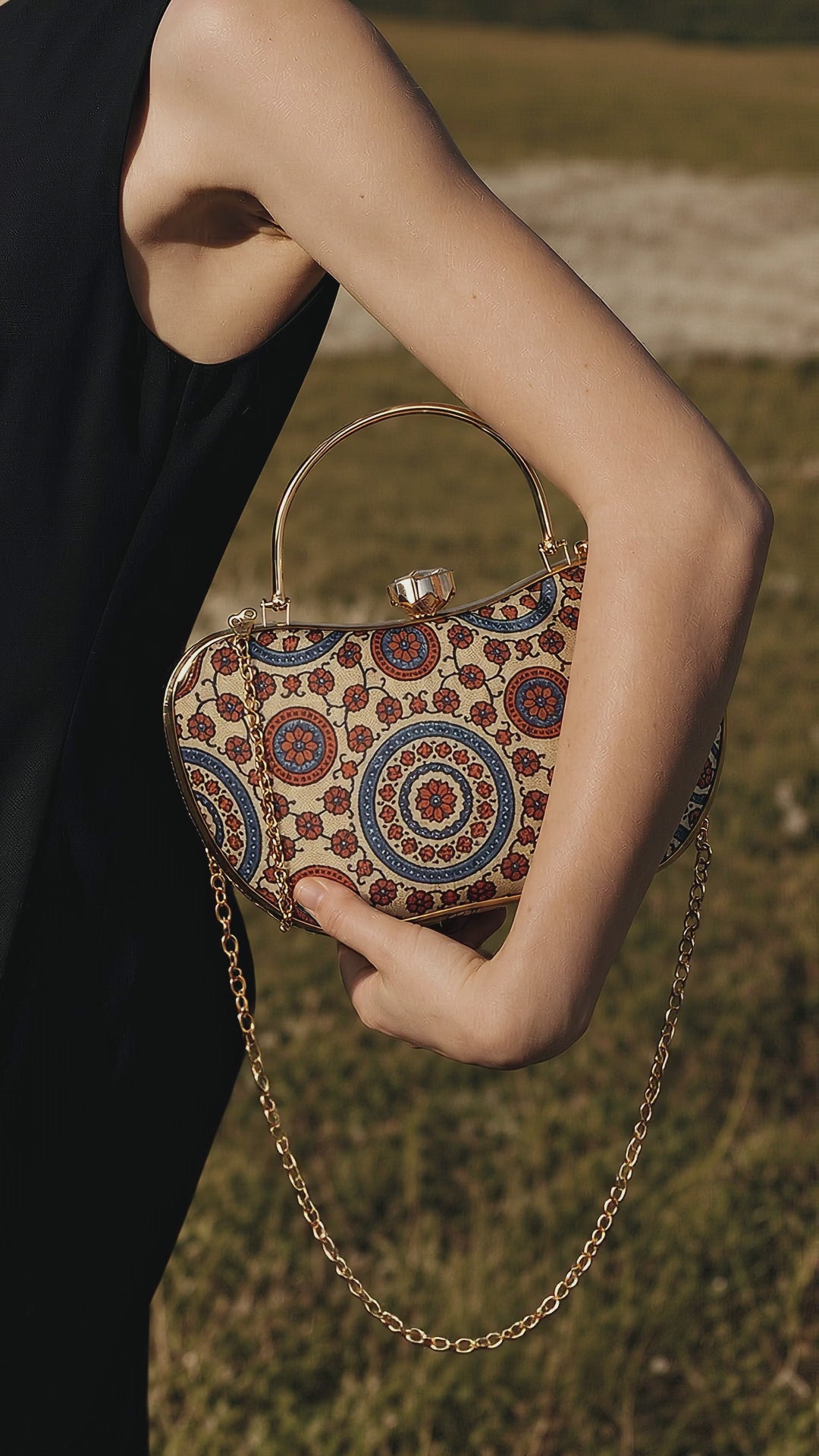Aaina ivory and maroon medallion Mashru silk handbag tucked under the arm, its long gold chain swaying in a light breeze