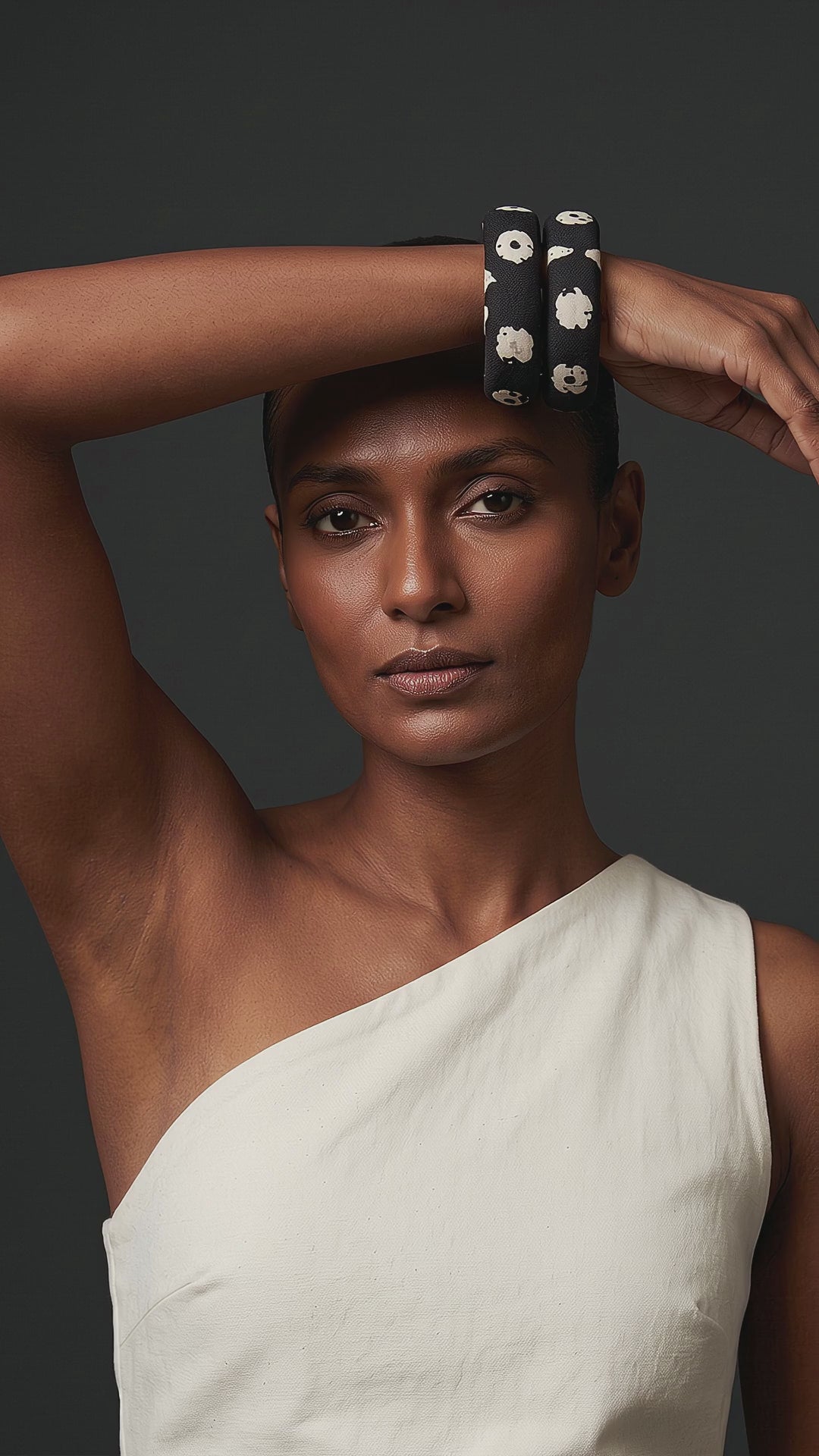 Kaali Katha black and white floral fabric bangles on a raised wrist resting on her head, worn with a white one-shoulder top (AI-generated styling video)