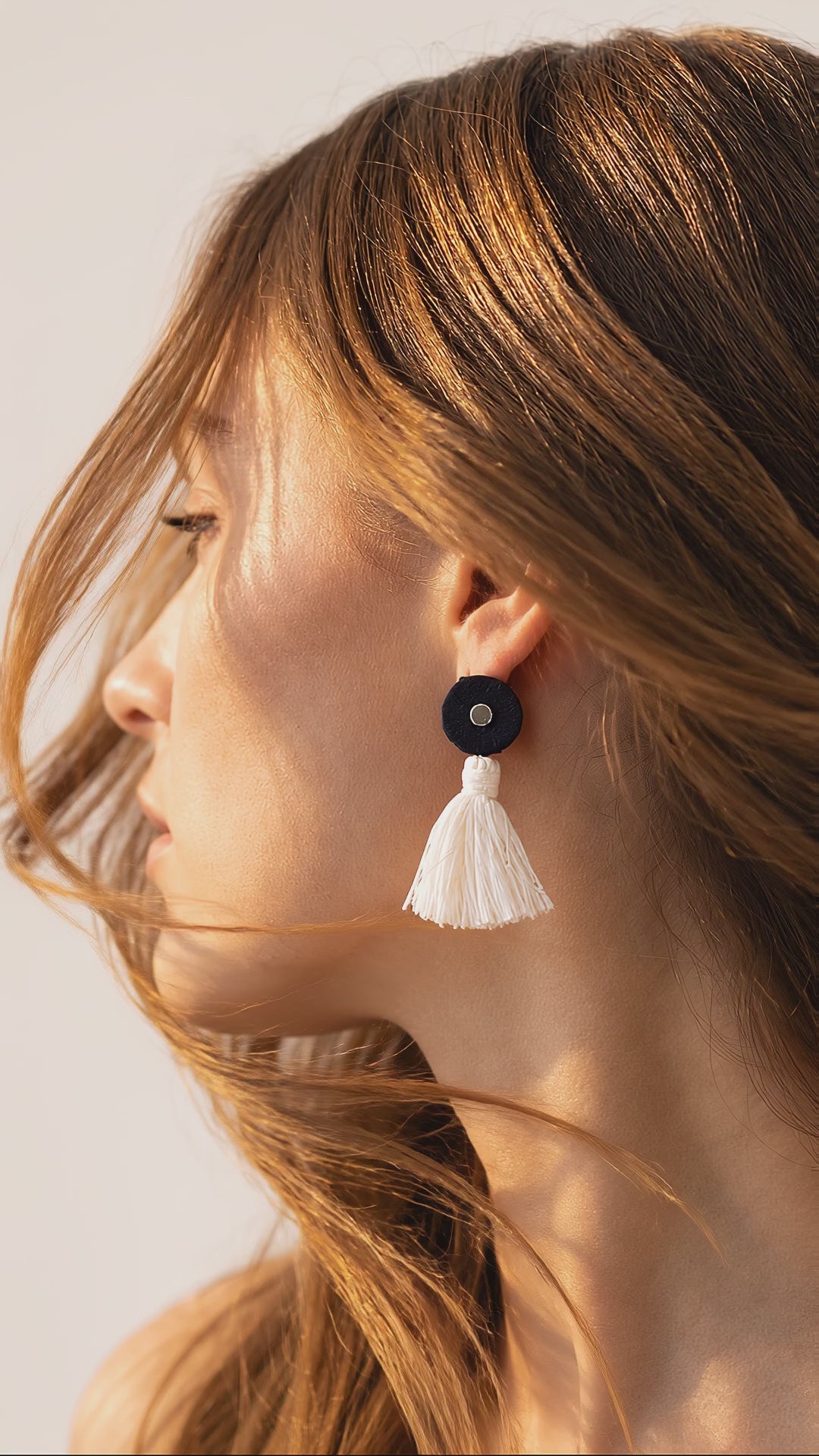 Navy mirror work earrings with an ivory cotton tassel swaying gently in a light breeze (AI-generated styling video)