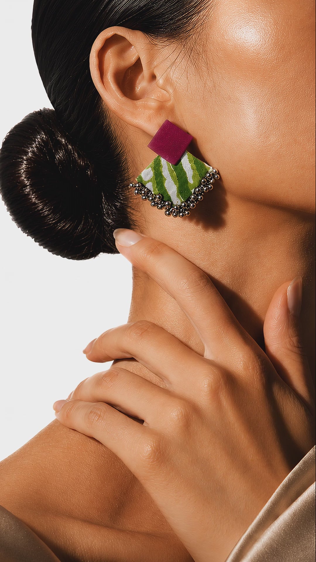 Geometric fuchsia and green striped fabric earrings with silver ghungroo bells swaying gently as the model tilts her head (AI-generated styling video)