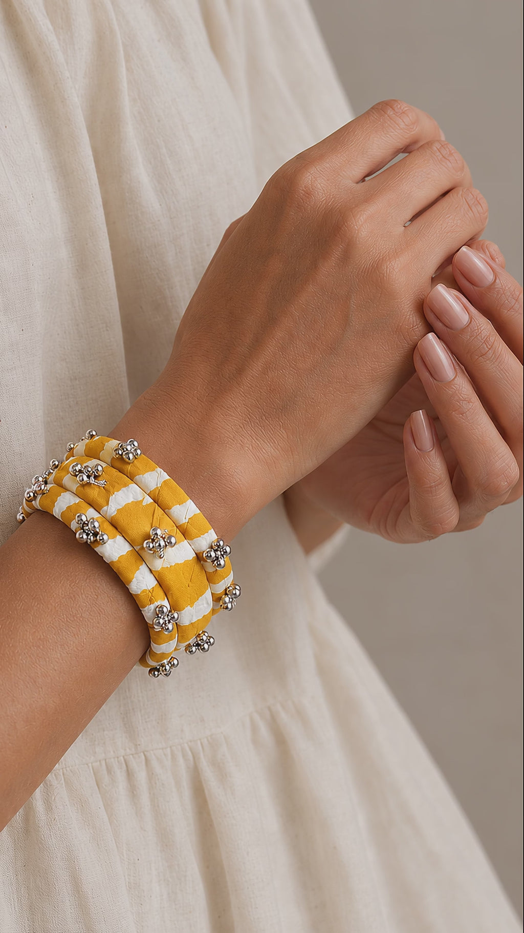 Lariya Bangles in yellow: leheriya fabric kada and bangles with ghungroo, shown in motion on the wrist