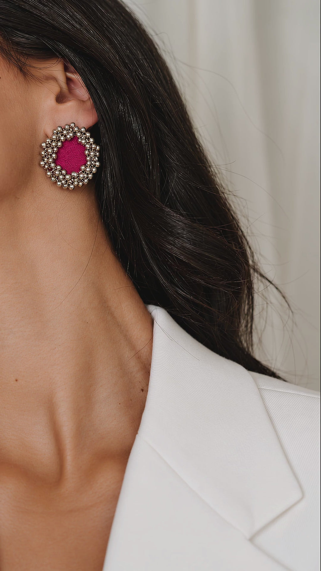 Fuchsia Pink Ghungroo Stud Earrings with two rows of tiny silver bells, worn with a white blazer, the light glinting on the bells (AI-generated styling video)