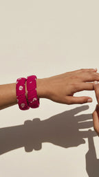 Gulnaar magenta pink floral fabric bangles on the wrist, the hand moving gently against a sunlit cream wall (AI-generated styling video)