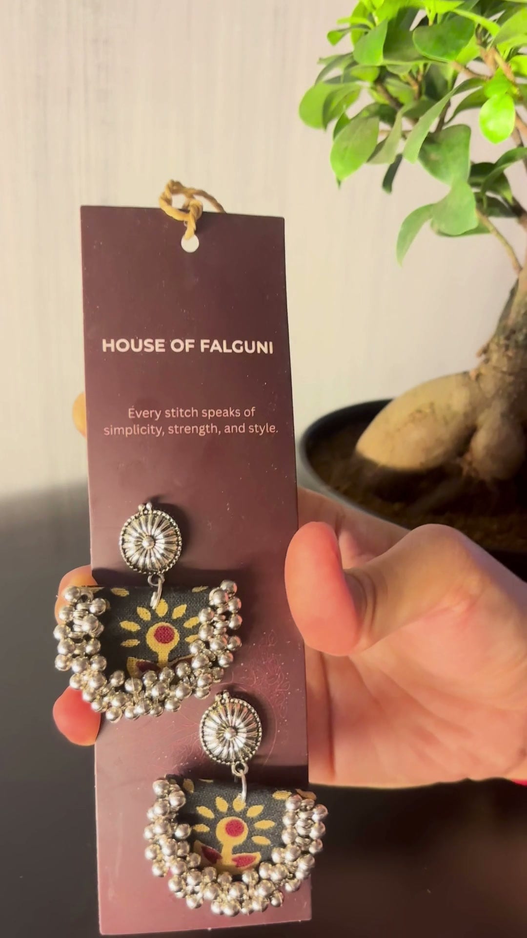 Black Chandbali Earrings with Ghungroo: Black Chandbali earrings on a House of Falguni card, brought up close: black fabric crescent printed with mustard flowers, kundan top and ghungroo bells