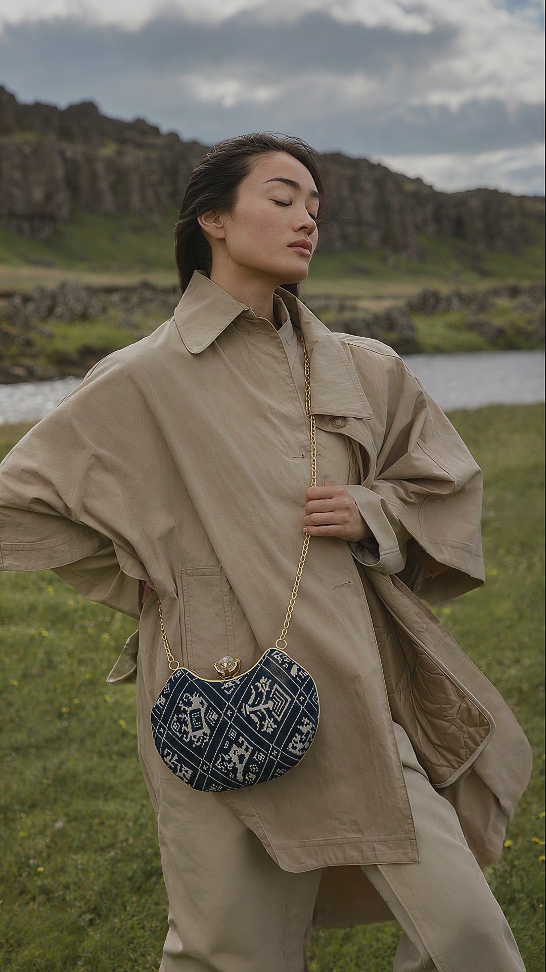 Neel Riwayat navy Ajrakh Mashru silk handbag worn crossbody over a trench coat as the wind moves her coat and hair