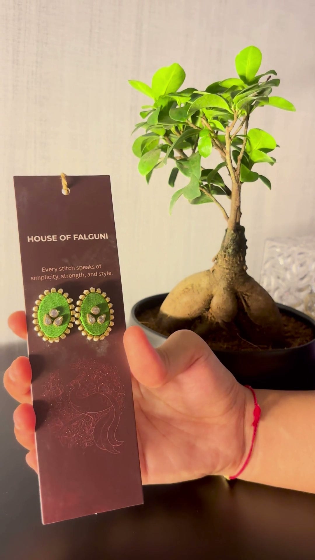 Mogra Parrot Green Oval Kundan Studs: Mogra Parrot Green Oval Kundan Studs on a House of Falguni card, tilted in the light: parrot green oval fabric studs with three kundan stones and a small kundan border