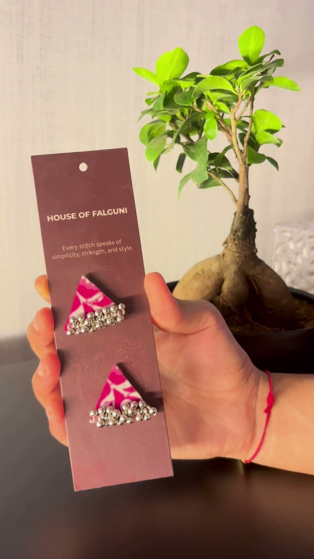 Riwaayat Noor Pink Triangle Earrings: Riwaayat Noor pink triangle earrings on a House of Falguni card, brought up close: pink block print with a white floral motif and a row of ghungroo bells