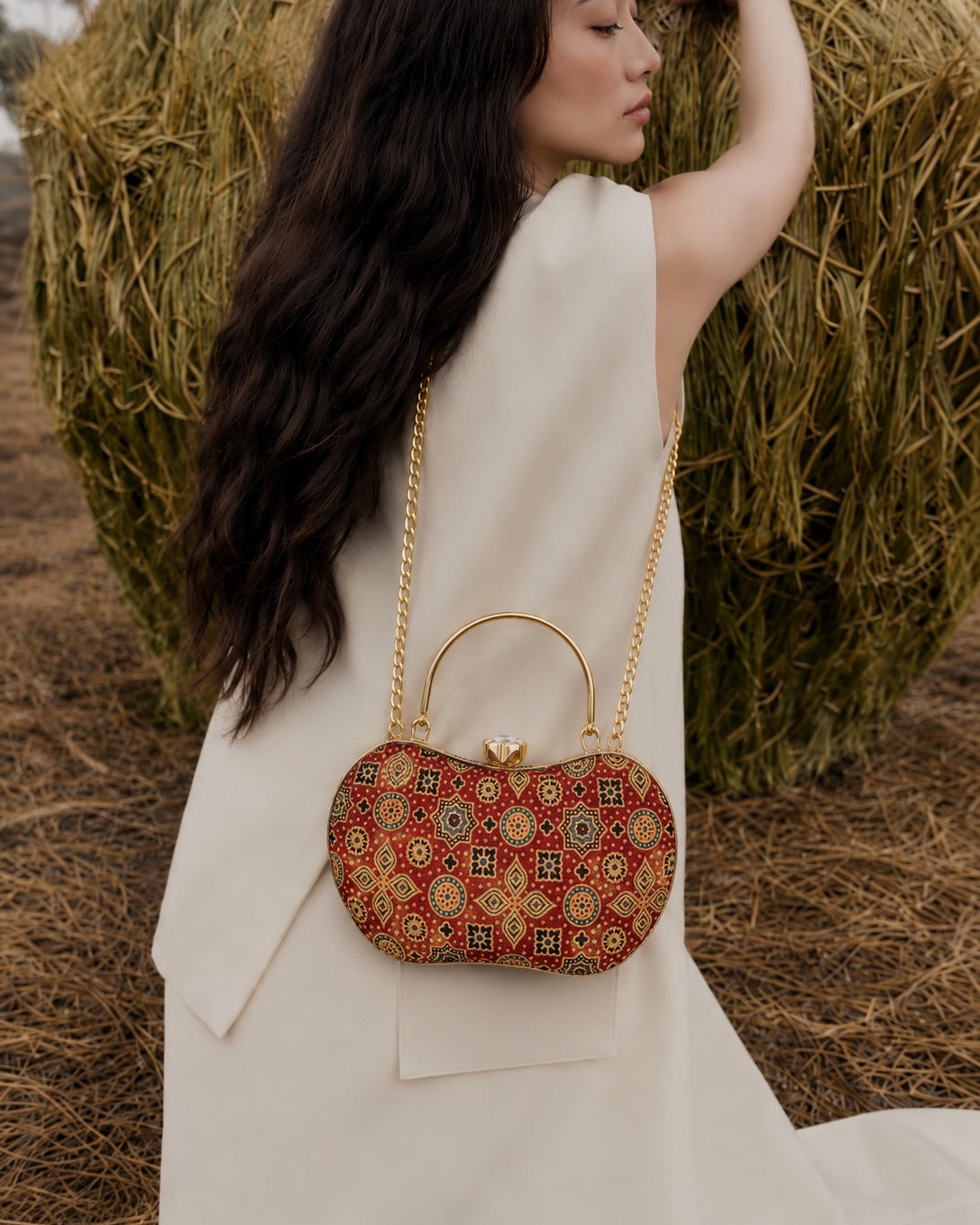 Rang Mahal red medallion-print Mashru silk handbag worn crossbody on its gold-tone chain over an ivory waistcoat