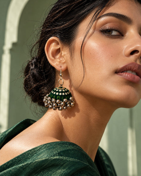 Rangrez Stripe Jhumka Earrings worn on a model in a green drape against a sage arch (AI-generated styling image)