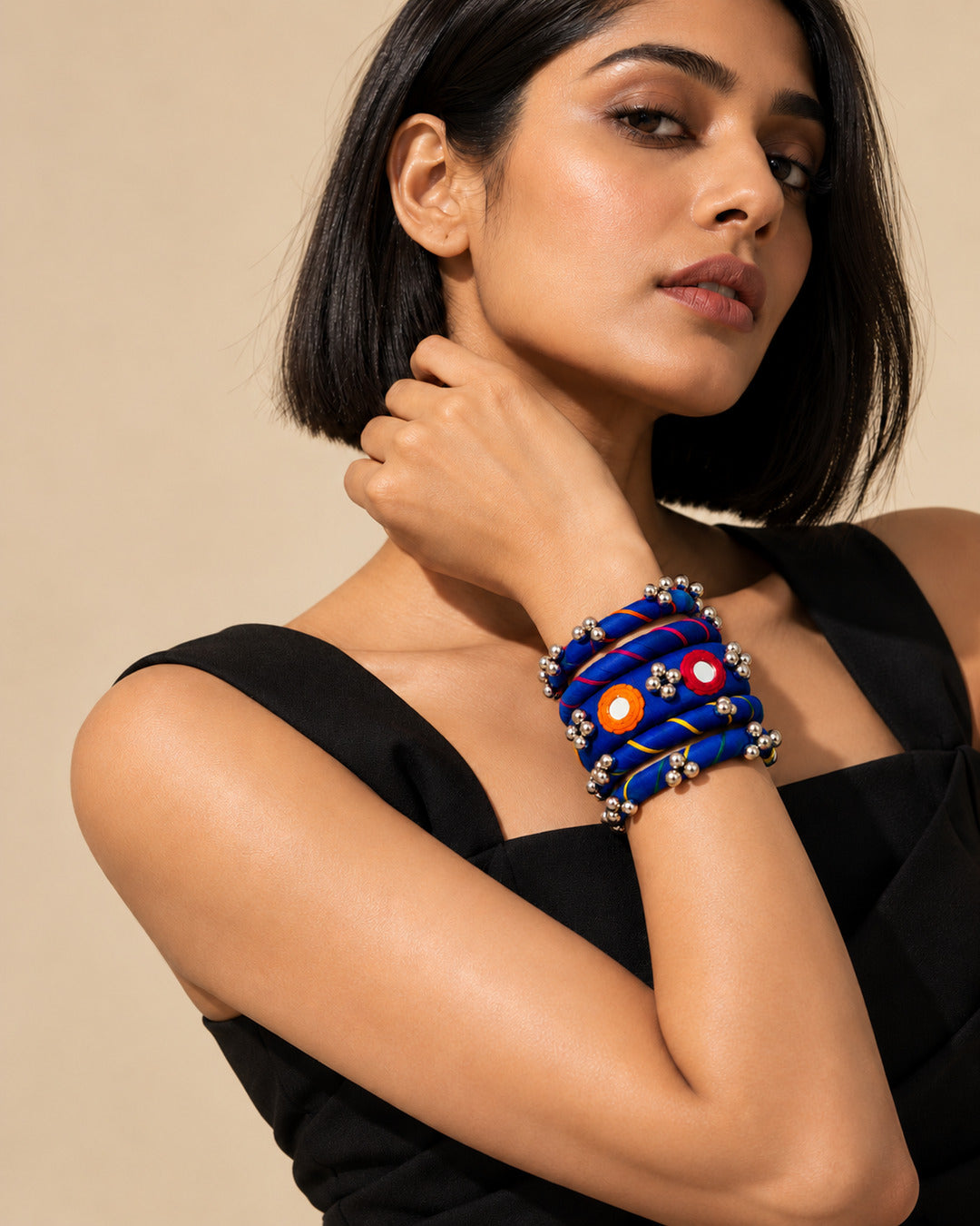 Rangriti blue fabric kada and four bangles with mirror work and ghungroo, worn by model in a black dress (AI-generated styling image)
