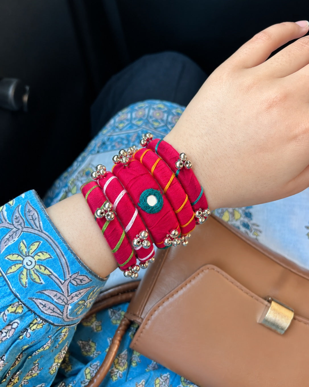 Rangriti pink ghungroo bangles worn with a blue printed kurta and a tan handbag