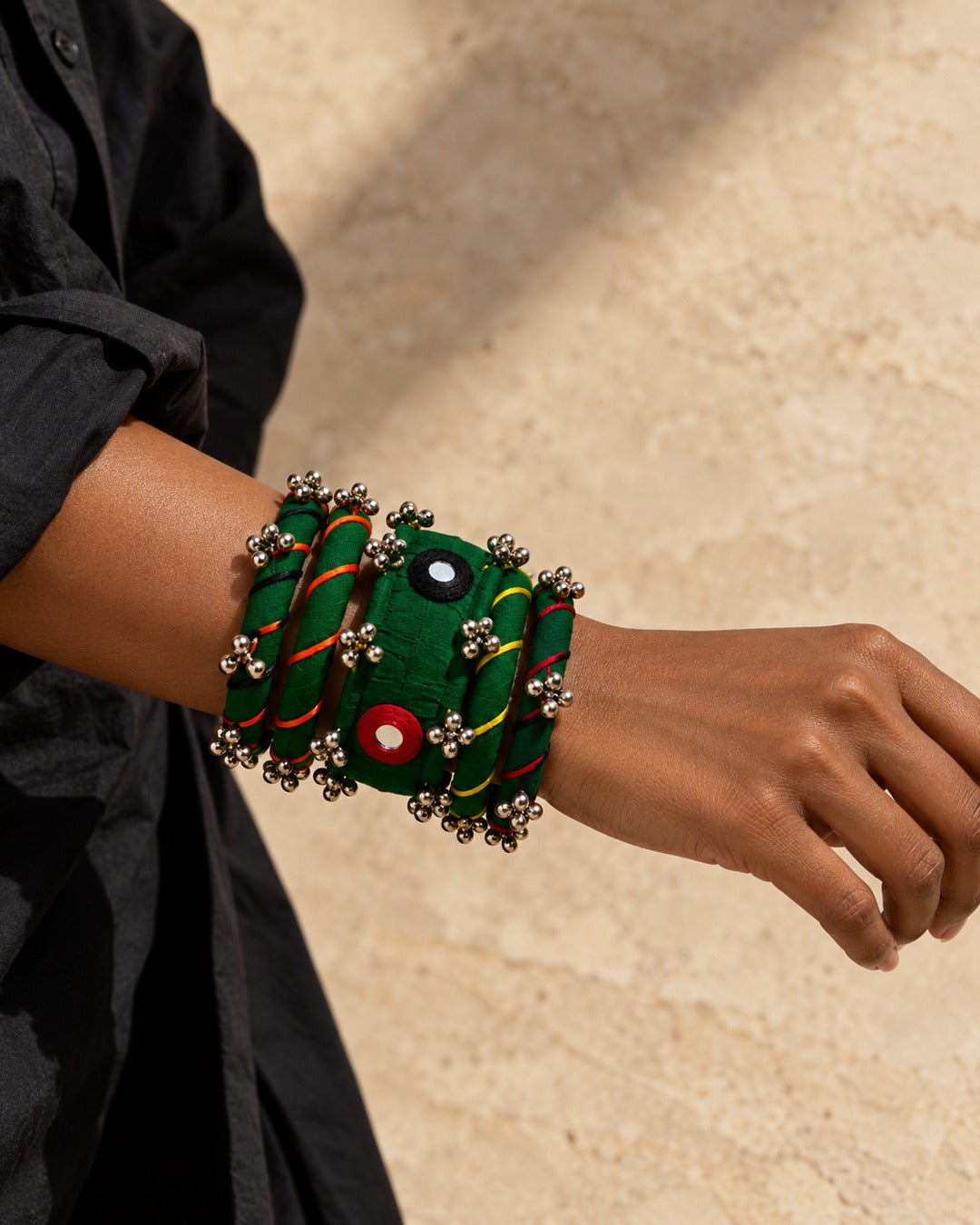 Rangriti green fabric kada and four bangles with mirror work and ghungroo, close-up on a model’s wrist (AI-generated styling image)