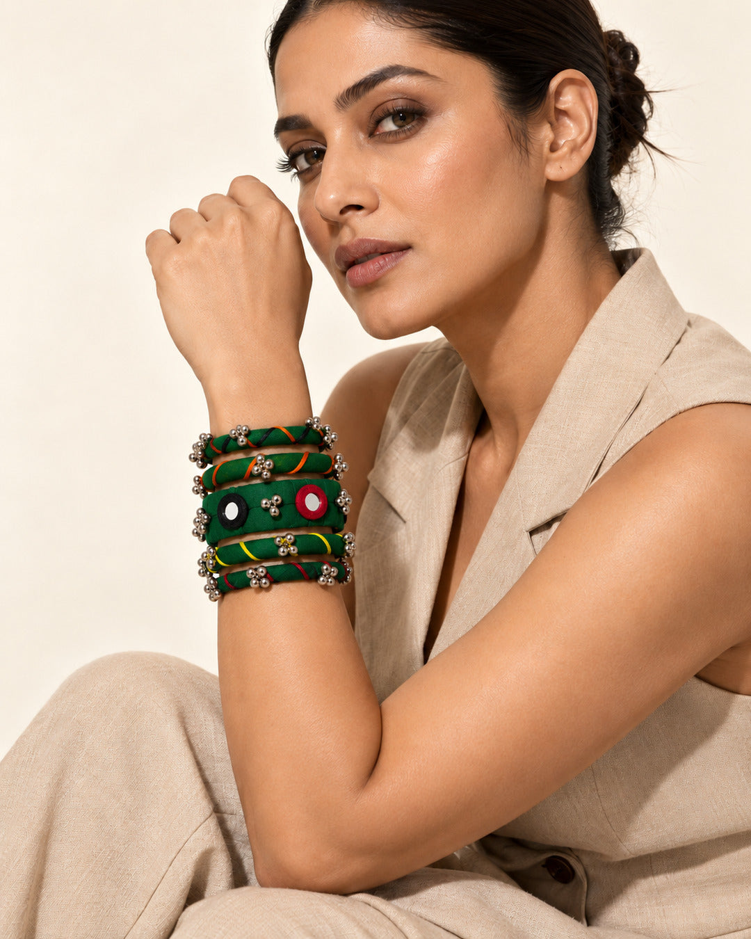 Rangriti green fabric kada and four bangles with mirror work and ghungroo, worn by model in a beige vest (AI-generated styling image)