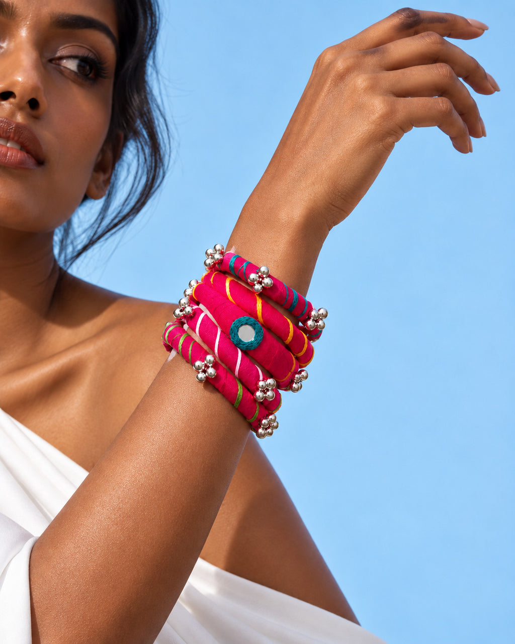 Rangriti pink fabric kada and four bangles with mirror work and ghungroo, worn by model with a lifted wrist (AI-generated styling image)