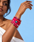 Rangriti pink fabric kada and four bangles with mirror work and ghungroo, worn by model with a lifted wrist (AI-generated styling image)