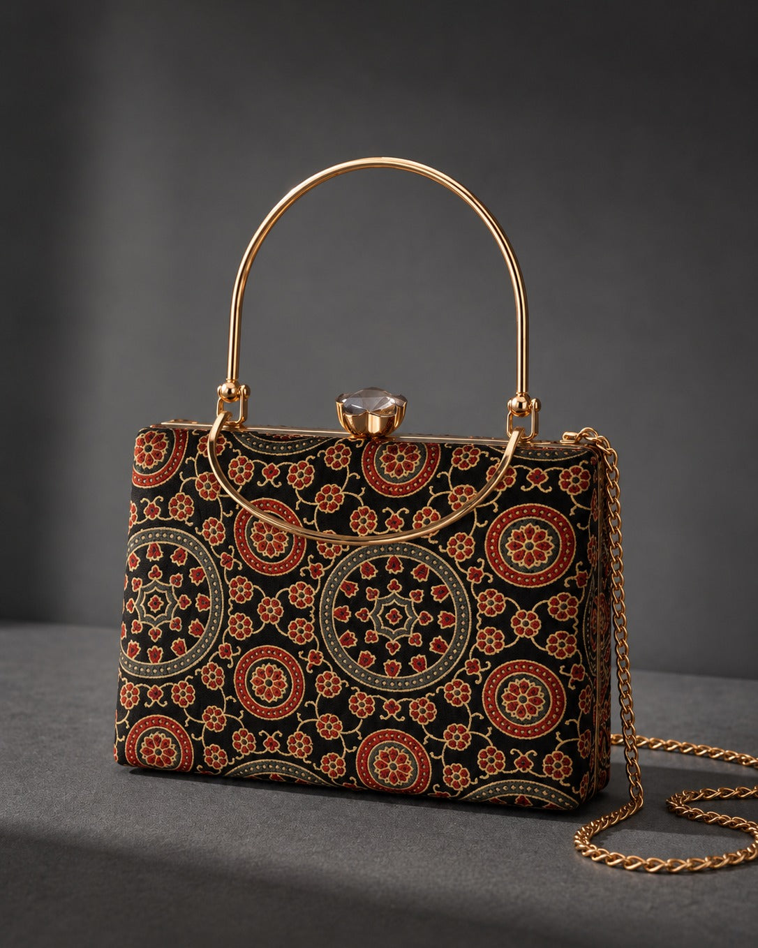 Ruhani rectangular Mashru silk handbag, black ground printed with maroon and teal concentric medallions, gold-tone frame and arched top handle