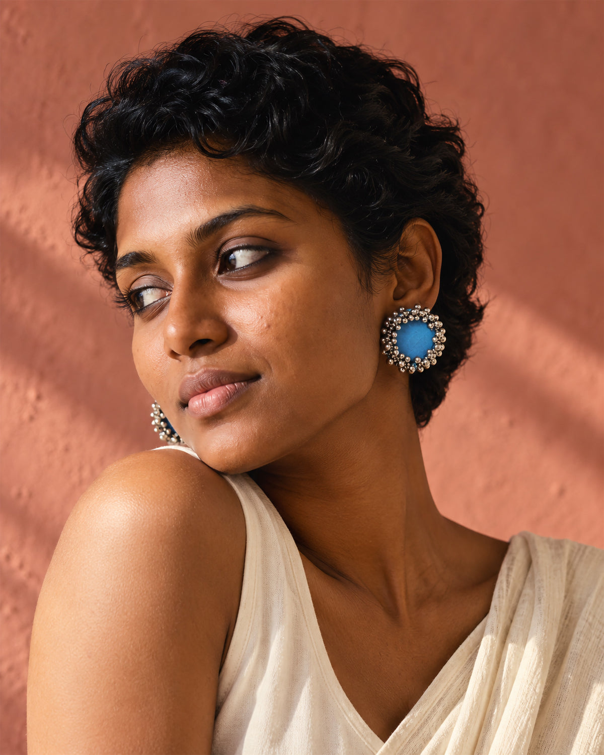 Sky Blue Ghungroo Stud Earrings, worn, cream top, terracotta pink wall