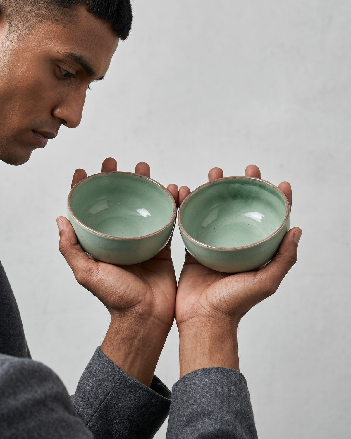 Tulsi Green Ceramic Serving Bowls, Reactive Glaze Katori (Set of 2) two bowls held in a model's hands, grey studio