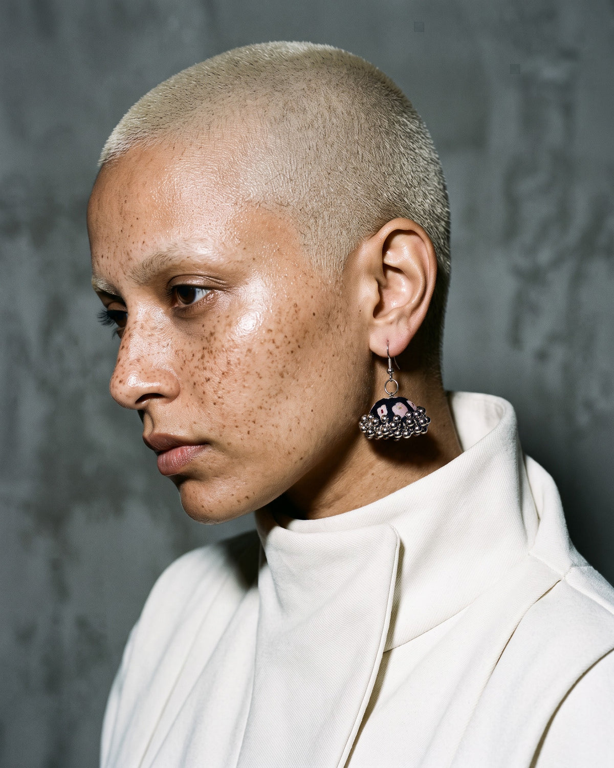 Vanraaj Jhumka Earrings worn on a model in a white high neck, grey studio (AI-generated styling image)